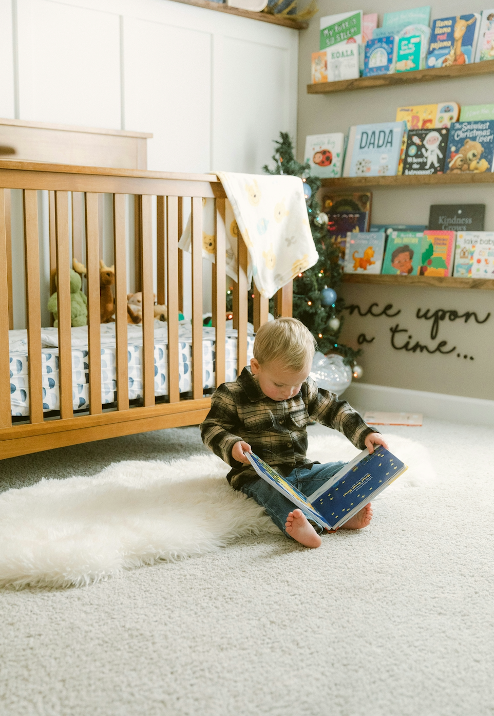 Child reading a book in a gender neutral nursery with a crib