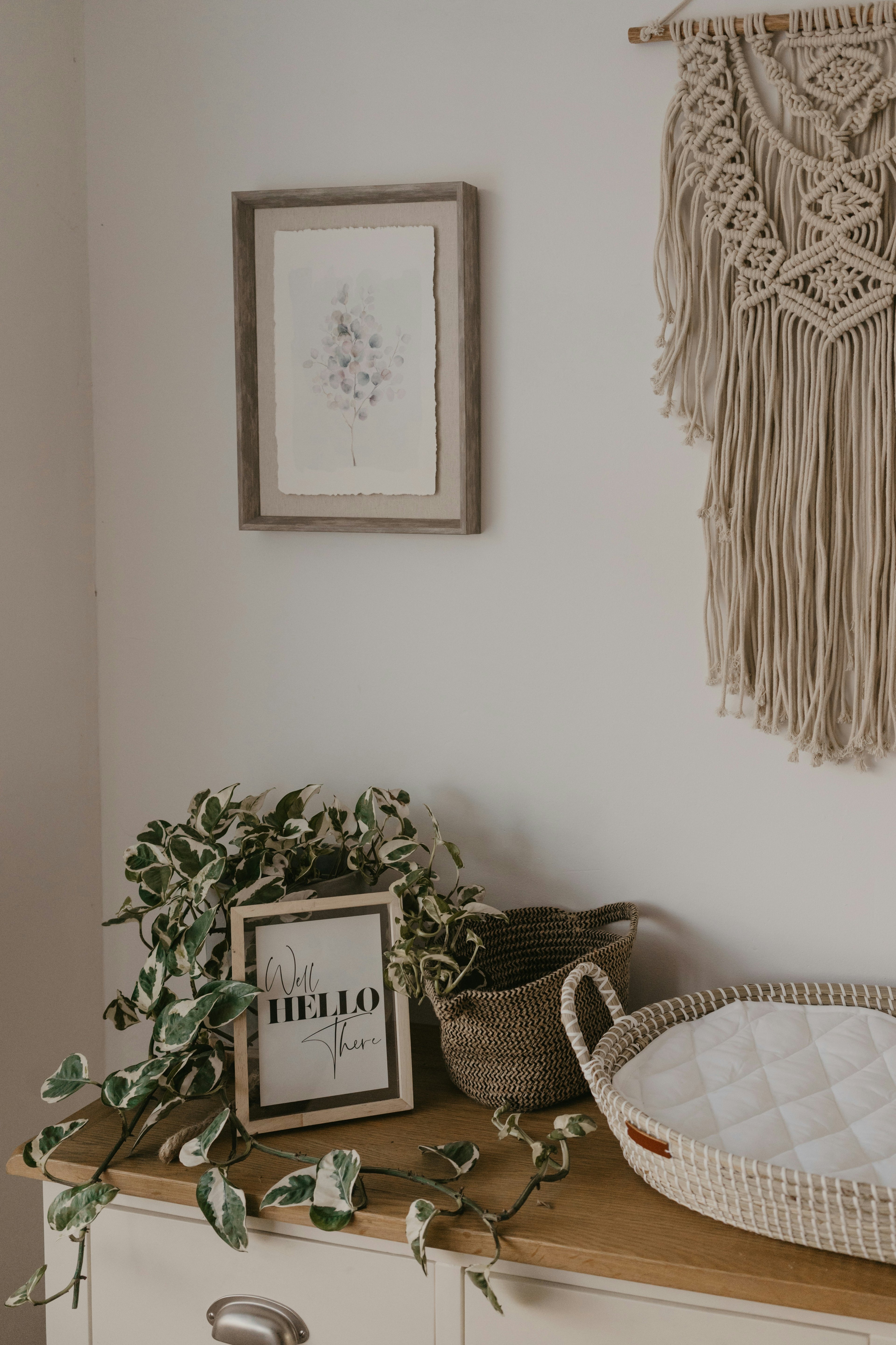 Gender neutral kids room with wooden shelf, framed picture, plant, and macrame wall hanging.