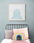 Children's bedroom with a bed featuring colorful pillows and a framed illustration of a beluga whale on the wall.