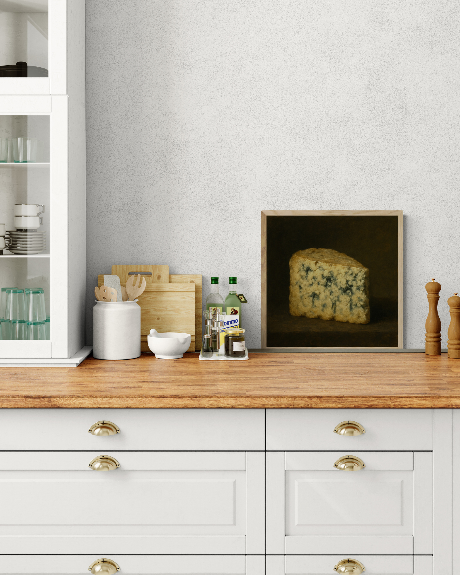 Wooden kitchen counter with white cabinets, kitchen utensils, and a framed picture of cheese.