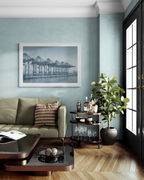 Modern living room with a green sofa, coffee table, and framed print of cranes in a port.