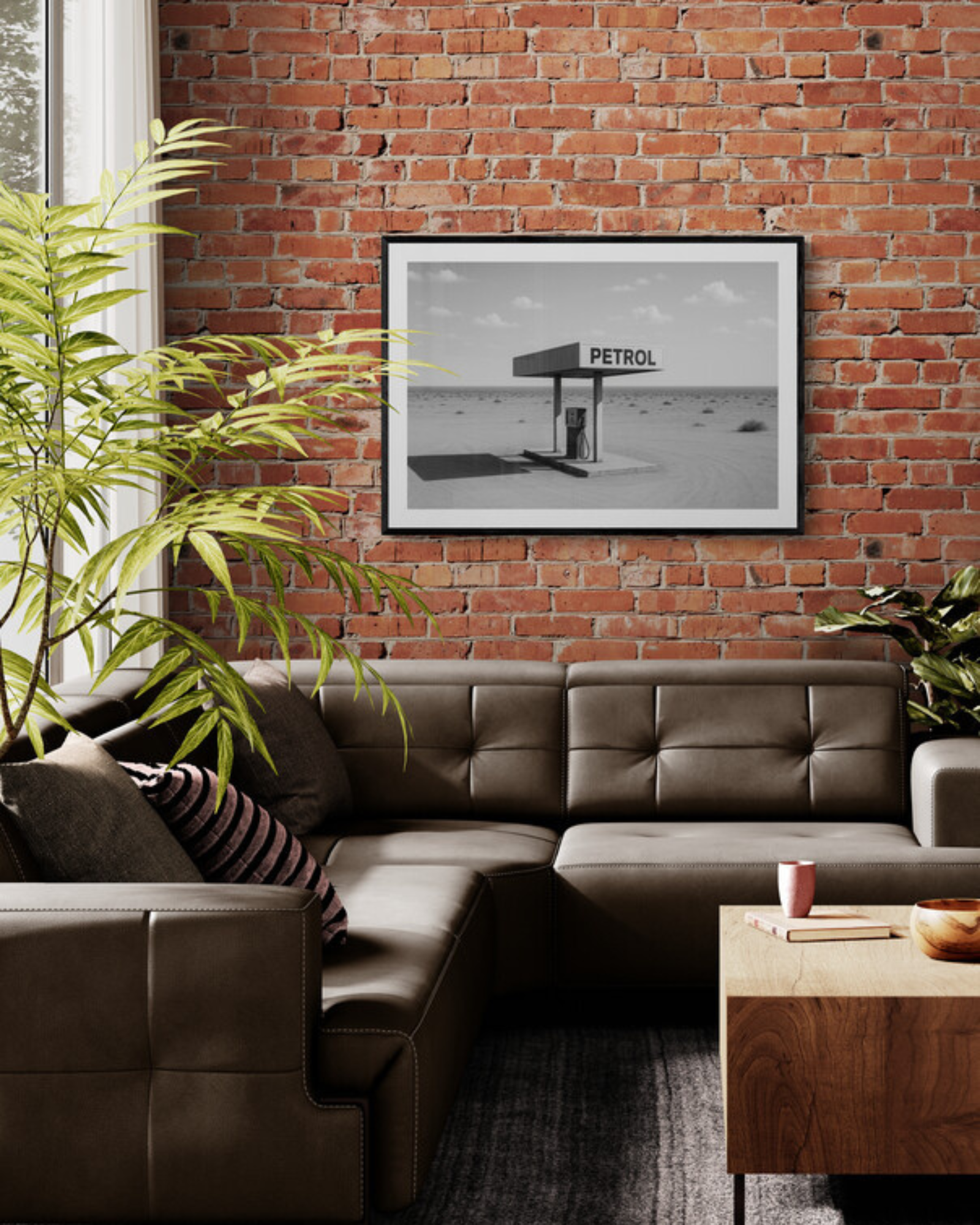 Living room with brown leather sectional, wooden coffee table, and framed black and white picture on brick wall.
