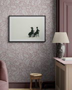 Framed black and white artwork on a wall with decorative wallpaper and furniture.