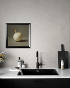 Modern kitchen with black faucet, countertop, and framed artwork of a white onion on gray wall.