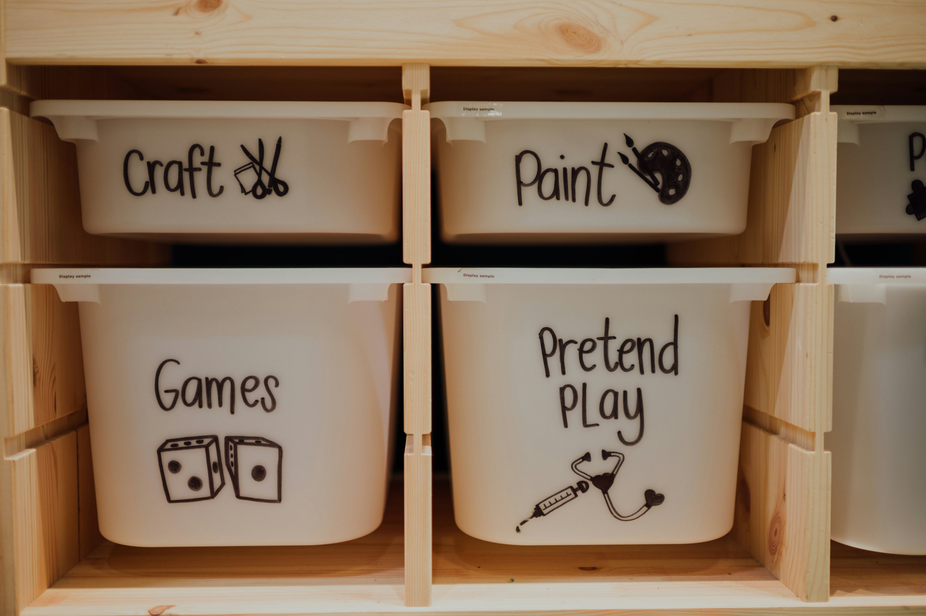 Storage bins labeled 'Craft', 'Paint', 'Games', and 'Pretend Play' in a wooden organizer.